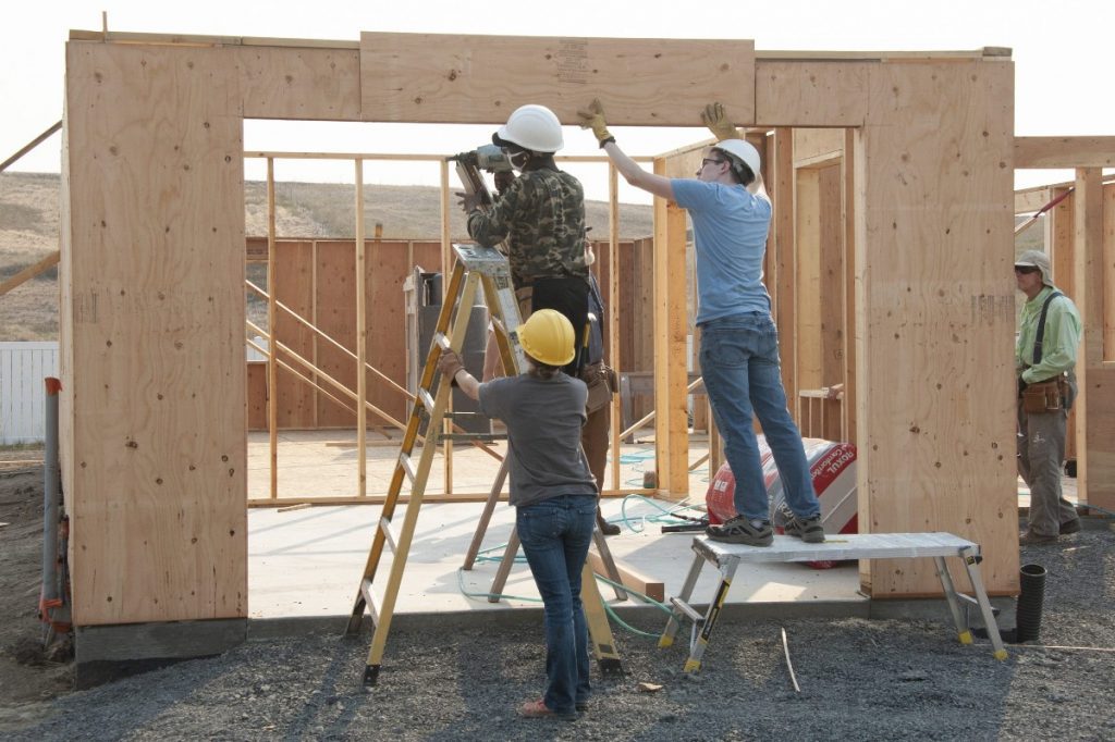 Volunteers Installing Sheathing Over the Garage Door at the Build Site