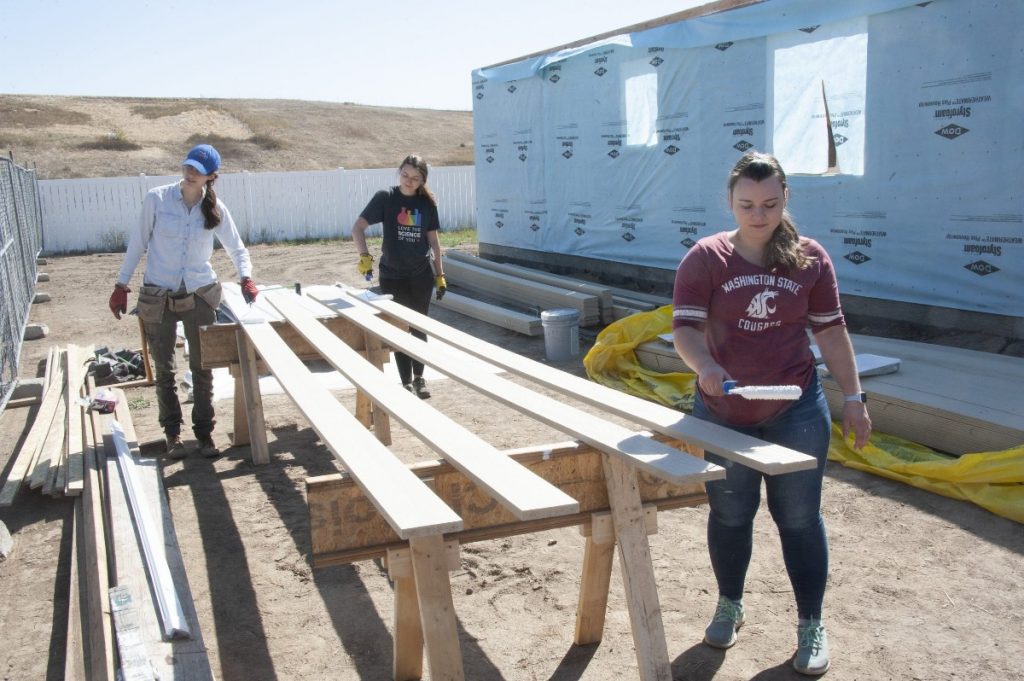 Volunteers Valerie, Belinda, and Julia Painting Trim at the Build Site