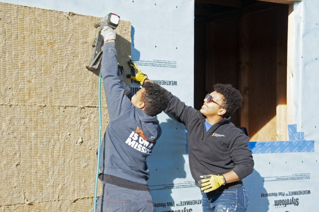 Volunteers Jackie and Rachel Installing Insulation at the Build Site.