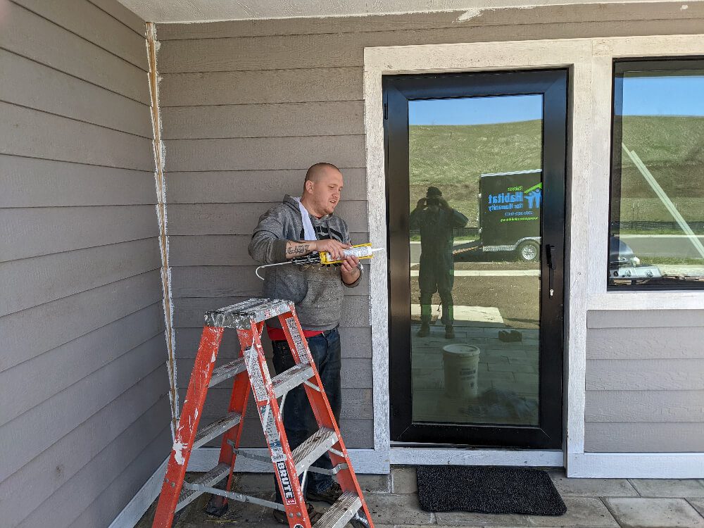 One of PHFH's volunteers, Kyle, caulking windows at a build site.