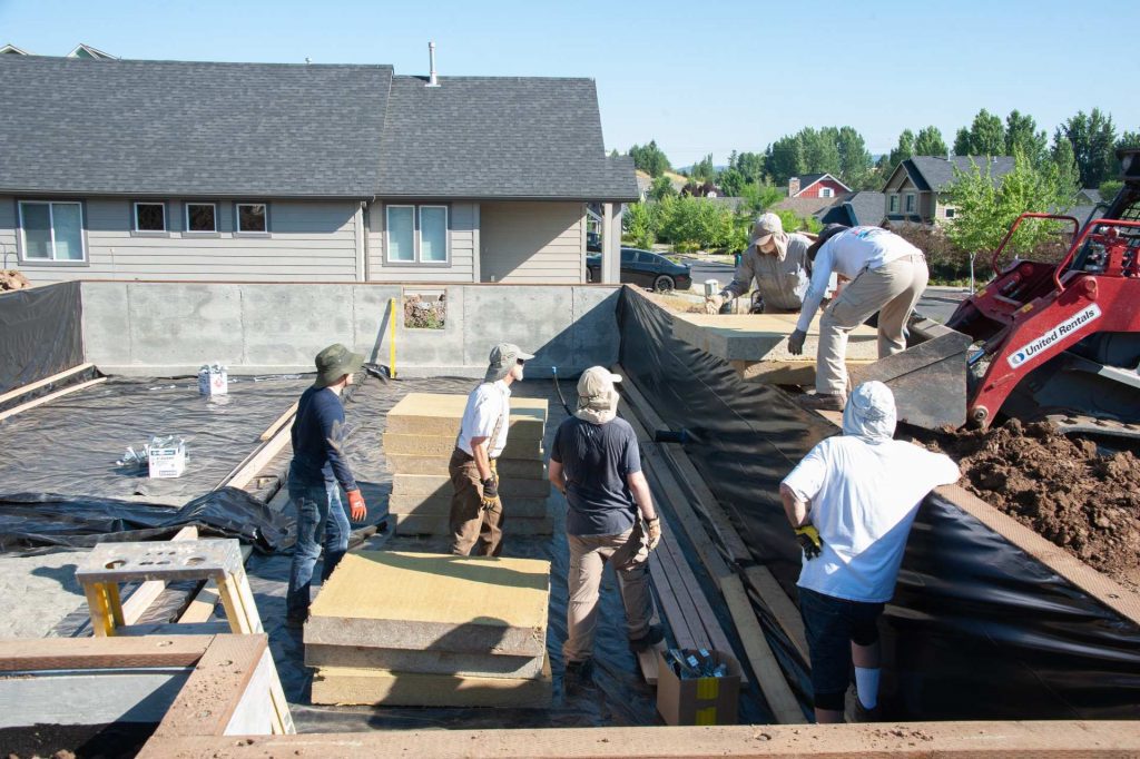 Volunteers stacking insulation in the crawlspace at the build site.