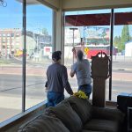 Two members of The 226 Men working together to reach the tall windows in the ReStore's furniture section